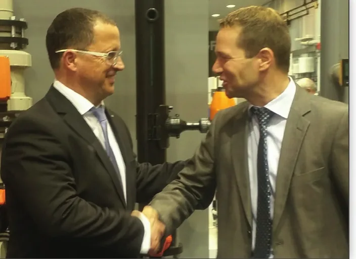 Handschlag zwischen Georg Fischer und Zickwolff, GF-Produkte im Hintergrund