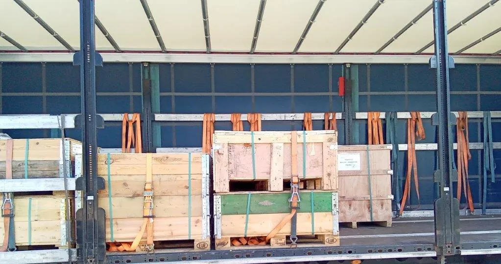 Caisses en bois cerclées sur palettes à rehausses dans un camion